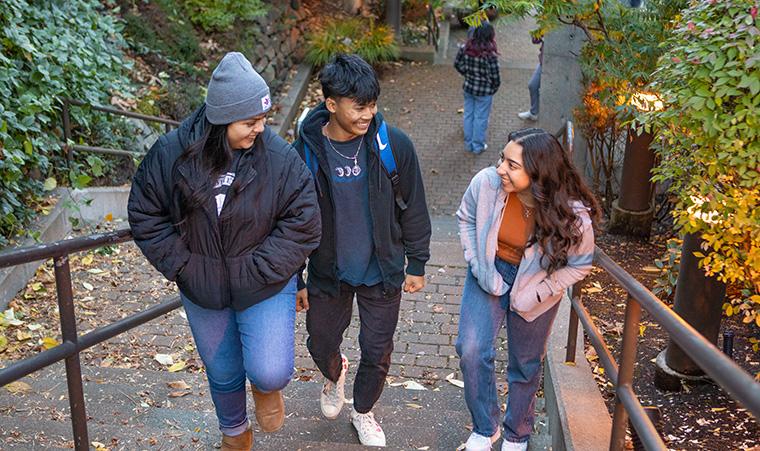 Three SPU students walk up a set of stairs on campus